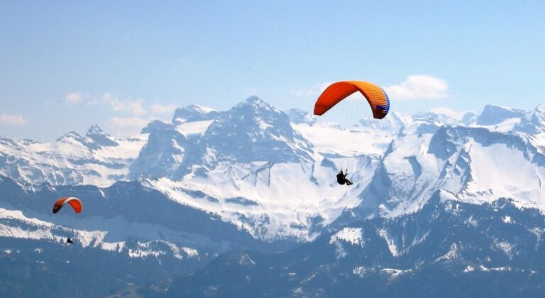 Paragliders soaring high above the snow-capped Himalayan mountains, enjoying a thrilling adventure with breathtaking views of the pristine peaks.